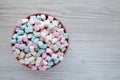 Rainbow Fruity Mini Marshmallows in a Pink Bowl on a white wooden background, top view. Flat lay, overhead, from above. Space for Royalty Free Stock Photo