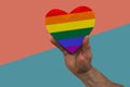 Rainbow gay pride symbol heart shaped in hands on geometric background in vibrant coral, turquoise, copy space Royalty Free Stock Photo