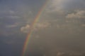A rainbow, in the gloomy sky between clouds, divides the picture in half