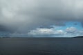 Rainbow in the grey and rainy clouds over the mountains of Helgeland archipelago Royalty Free Stock Photo