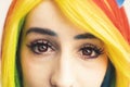 Rainbow-haired girl with red eyes and long dark lashes looking into the camera extreme close-up shot Royalty Free Stock Photo