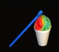 Rainbow Hawaiian Shave ice, Shaved ice or snow cone dessert in a white cup with a spoon straw against a black background. Royalty Free Stock Photo