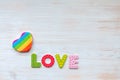 Rainbow heart pillow and word LOVE in wood letters on wooden vintage board. Mockup for LGBT. Valentines day concept Royalty Free Stock Photo