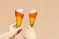 rainbow ice cream cone - two hands holdling ice cream cones in rainbow colors at hot summer day Royalty Free Stock Photo