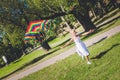Rainbow kite in the sky. multirace girl playing and running with kite. Royalty Free Stock Photo