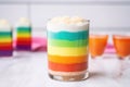 rainbow layered latte in a clear glass on a light pastel table