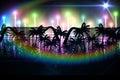 Rainbow lens flare over silhouette of palm trees against light trails against black background