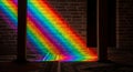 Rainbow light spectrum cast on brick wall and patterned carpet indoors Royalty Free Stock Photo