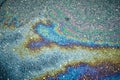 Rainbow-like oil spill creating captivating designs on the wet asphalt surface. Royalty Free Stock Photo