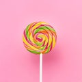 Rainbow lollipop swirl on a white stick over pink background. Top view, copy space Royalty Free Stock Photo