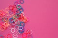 Rainbow loom bands bracelets on pink background. Colorful ties for waving hair. Children hobby - handmade bracelets