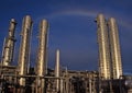 A rainbow looms over a refinery gleaming in the late day sun.