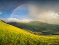 Rainbow in the mountain valley during rain Royalty Free Stock Photo