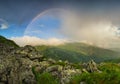 Rainbow in the mountain valley during rain Royalty Free Stock Photo