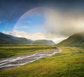 Rainbow in the mountain valley during rain Royalty Free Stock Photo