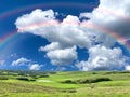 Rainbow nature landscape contryside green grass field trees and sun beam on cloudy fluffy blue and pink sky