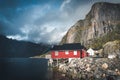 Rainbow ofer red houses rorbuer of Reine in Lofoten, Norway with red rorbu houses, clouds, rainy blue sky and sunny Royalty Free Stock Photo