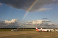 Rainbow over airplanes on airport Tegel, Berlin. Blue sky and dark rain clouds at same time. Royalty Free Stock Photo