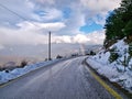 Rainbow over asphalt mountain road with snow and cloudy sky. Corinthia, Greece Royalty Free Stock Photo