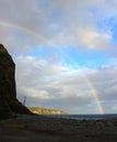 Rainbow Over bright blue sky and Ocean and Rocky beach Royalty Free Stock Photo