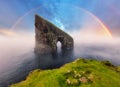 Rainbow over coast cliff in ocean Drangarnir in Faroe island. Sunset landscape