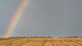 Rainbow over a field on a hot summer stormy day with a dark sky in the background.