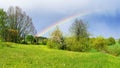 Rainbow over a green field outside the city. Natural rural landscape with rainbow after heavy rain in summer season. Precipitation Royalty Free Stock Photo