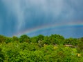 Rainbow over the hill with several garden houses a few moments after heavy rain Royalty Free Stock Photo