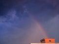 Rainbow over the house rises to dark heavy rain clouds Royalty Free Stock Photo