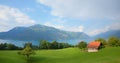 rainbow over lake Thunersee, green pasture with hut, mountain landscape Berner Oberland, Switzerland