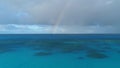 Rainbow over the ocean. Flying over a reef.