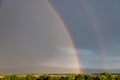 Rainbow over a quaint village and meadows, after the rain, copy space, wallpaper.