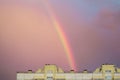 Rainbow over the roof of a multi-storey city house in the evening pink sunset sky after the rain, summer fantastically beautiful Royalty Free Stock Photo