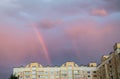 Rainbow over the roof of a multi-storey city house in the evening pink sunset sky after the rain, summer fantastically beautiful Royalty Free Stock Photo