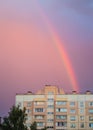 Rainbow over the roof of a multi-storey city house in the evening pink sunset sky after rain, summer fantastically beautiful Royalty Free Stock Photo