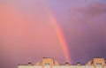Rainbow over the roof of a multi-storey city house in the evening pink sunset sky after the rain, summer fantastically beautiful Royalty Free Stock Photo
