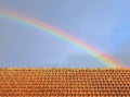rainbow over the rooftop of an old house with rainy weather clouds on sky Royalty Free Stock Photo