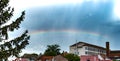 Rainbow over rooftops with rain clouds Royalty Free Stock Photo