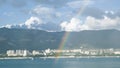 Rainbow over sea with yachts and mountain coast. Concept. Seascape with rainbow on background of coast with town Royalty Free Stock Photo