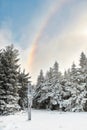 A rainbow over the signpost at a mountain crossroads, the sun`s rays illuminate the fog on a winter afternoon.