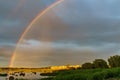 Rainbow over stony seacoast by sunset Royalty Free Stock Photo
