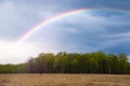 Rainbow over stormy sky. Rural landscape with rainbow over dark stormy sky in a countryside on a springtime day