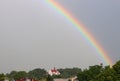 Rainbow over the temple in a dark and rainy sky. Unfavorable weather conditions. A beautiful atmospheric phenomenon of refraction Royalty Free Stock Photo