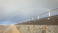 Rainbow over a UK beach and sea ocean defence brick wall Royalty Free Stock Photo