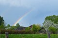 Rainbow over the village in summer, Russian rustic rural landscape. old russian wooden house in the field Royalty Free Stock Photo
