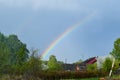 Rainbow over the village in summer, Russian rustic rural landscape. old russian wooden house in the field Royalty Free Stock Photo