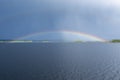 Rainbow over water and dark rain clouds on the sky Royalty Free Stock Photo