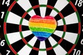 Rainbow painted colored crayons on paper heart glued to dartboard on sunny day