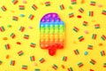 Rainbow Pop it fidget toy next to the colorful marmalade candies on yellow background.