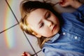 Rainbow reflection on the face of a little girl lying on the floor Royalty Free Stock Photo